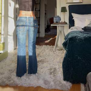 Säljer ett par snygga blå bootcut jeans i bra skick. De är lågmidjade och har coola broderade detaljer på bakfickorna. Midjemått: 34cm rakt över, innerbenslängd: 74cm💋