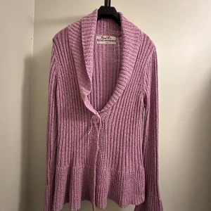 Ljuslila stickad kofta  - Superfin ljuslila stickad kofta från Joy of Love i storlek L! . Den har en mysig krage och knytband framtill. Perfekt för kyliga dagar och ger en avslappnad men stilren look. Helt oanvänd! 