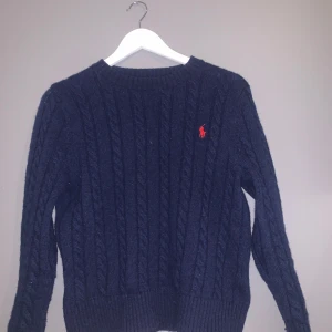 Ralph lauren stickad tröja mörkblå - Säljer en snygg mörkblå stickad tröja från Polo Ralph Lauren. Jag säljer den då den är för liten nu, men har använt den försiktigt. Den har ett klassiskt flätmönster och den ikoniska röda loggan på bröstet. Perfekt för kyliga dagar och ger en stilren look. Passar både till vardags och lite finare tillfällen. Inga synliga skråmor eller fläckar. Storlek small pris 699köpt för 1700 pris kan diskuteras. Kom Dm för mer bilder