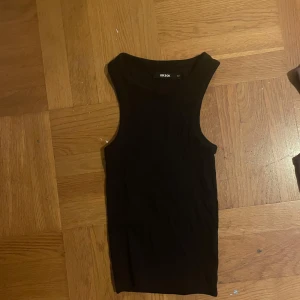 Svart ärmlös topp från bikbok - Säljer en stilren svart ärmlös topp från bikbok Perfekt som ett basplagg i garderoben. Toppen är i ett mjukt och stretchigt material som ger en bekväm passform. Passar till både vardag och till festliga tillfällen 