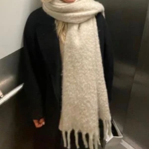 Beige/vit  halsduk från Stockh lm Studio - Säljer en supermysig tjock beige halsduk från Stockh lm Studio. Den är perfekt för kyliga dagar och har långa fransar i ändarna som ger en stilren look. Passar perfekt till både höst och vinteroutfits. Bara använd en gång säljer då jag köpt en annan 👍🏼200*45+17 cm💗Första bilden lånad! 