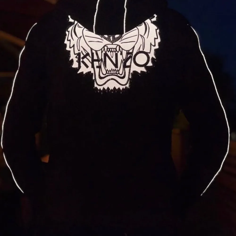 Säljer en snygg röd hoodie från Kenzo med ett coolt tigerbroderi på bröstet och ryggen. Den har en dragkedja framtill och långa ärmar med vita detaljer längs sidorna. Perfekt för höst och vinter, både varm och stilren. Passar lika bra till vardags som till en chill festkväll. Själva tröjan lyser även när man ute oavsett om det är ljus eller helt mörkt. Kolla bild 3&4. . Tröjor & Koftor.