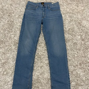 Lee jeans - Säljer ett par klassiska blå jeans från Lee i mycket bra skick. De har en straight passform och är tillverkade i slitstarkt denim. Perfekta för vardagsbruk och kan enkelt matchas med olika outfits. Dragkedja och knapp framtill samt fem fickor.