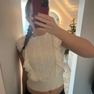 Vit spetsblus med volangdetaljer - Säljer en superfin vit blus med spets och volangdetaljer. Den är kortärmad och har en söt, croppad passform som passar perfekt till både vardag och fest. Perfekt för sommardagar eller en mysig vårkväll. 🕊️