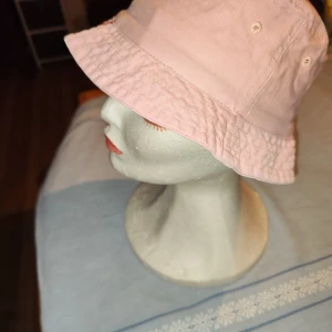 Rosa bucket hat - Snygg rosa bucket hat i bomull. Perfekt för sommardagar med sin avslappnade stil och bekväma passform. Hatten har en klassisk design med en bred kant som ger skugga och skydd mot solen.