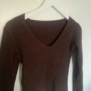 Brun stickad tröja - Säljer en mysig brun stickad tröja med v-ringning. Tröjan har långa ärmar och en enkel design som passar perfekt för kyligare dagar. Perfekt för att hålla sig varm och stilren.