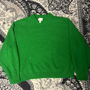 Grön tröja från H&M - Säljer en snygg grön tröja från H&M. Tröjan har en klassisk design med rund hals och långa ärmar. Perfekt för att lägga till en färgklick i garderoben. 