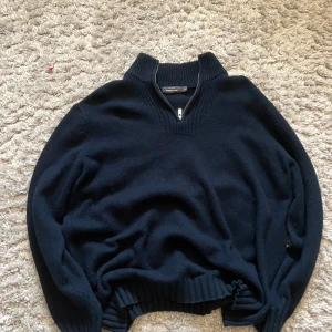 Ull zip up - Säljer en stilren mörkblå tröja från Dressmann i storlek XL. Tröjan har en praktisk dragkedja och är tillverkad av en blandning av bomull och ull, vilket gör den både bekväm och varm. Perfekt för kyligare dagar!