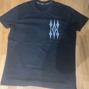 Svart t-shirt från Amiri - Snygg svart t-shirt från Amiri med unikt mönster i vitt på både fram- och baksidan. Perfekt för dig som vill ha en stilren men ändå iögonfallande look. T-shirten har en normal passform. 