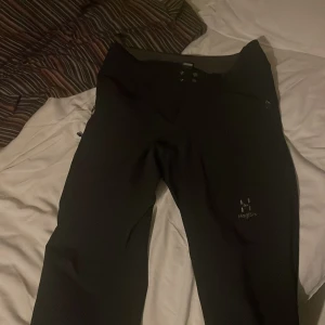 Svarta byxor från Haglöfs - Säljer ett par svarta byxor från Haglöfs. Byxorna har en stilren design med knappar och dragkedja framtill. Perfekta för utomhusaktiviteter och har en bekväm passform.