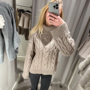 Beige stickad polotröja - Säljer en mysig beige stickad polotröja med flätmönster från h&m. Tröjan har långa ärmar och en hög krage som håller dig varm. Helt oanvänd med prislappen kvar. Storlek S men sitter mer som xs🥰