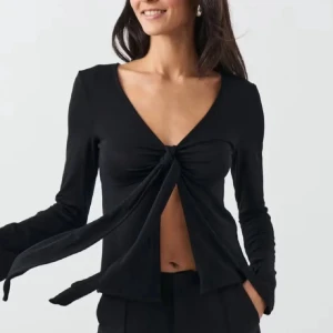 Svart långärmad topp med knyt - Svart långärmad topp från Gina Tricot med v-ringning och knyt framtill. Storlek XS och endast använd 1 gång. Säljer då den ej kommer till användning och lite för liten för mig. Skriv för fler bilder eller funderingar 💕