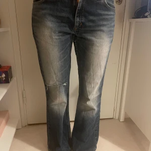 Blå jeans med slitningar - Säljer ett par blå jeans med slitningar på knäna och en klassisk femficksdesign. Jeansen har en straight passform och en bekväm midwaist. Perfekta för en avslappnad stil. Storlek 31-31