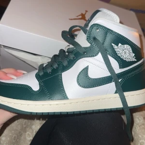 Nike Air Jordans i grönt och vitt - Snygga Nike Air Jordans i en fräsch grön och vit färgkombination. Skorna har klassisk snörning och den ikoniska Air Jordan-loggan på sidan. Perfekta för att ge din outfit en sportig touch. Säljer då dom e försmå på mig och orkar inte skicka tillbaka, har kvitto om det är så! Endast provade 