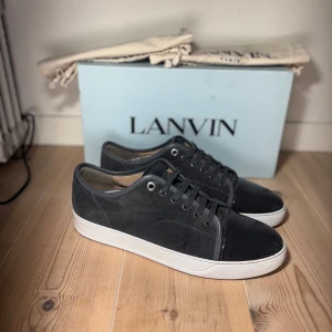 Lanvins uk 10 - Snygga grå sneakers från Lanvin med en stilren design. Skorna har en kombination av mocka och skinn, med en blank svart tå och vita sulor. Perfekta för en trendig look. Passar 44/45 allt og ingår vid köp. Unik färg som är väldigt sällsynt och eftertraktad.