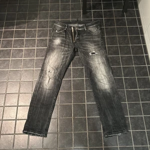 DSQUARED2 Jeans - Snygga svarta jeans från DSQUARED2 med slitna detaljer och en cool tvättad look. De har en dragkedja och knappar framtill samt klassiska fem fickor. Perfekta för en trendig stil. Storlek 46 passar som 31/32.