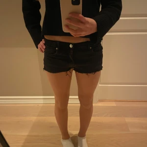 Svarta jeansshorts - Snygga svarta jeansshorts med låg midja och fransiga kanter. Perfekta för en avslappnad stil. De har en klassisk femficksdesign och knappar framtill. Säljer då de inte kommer till användning!🩷