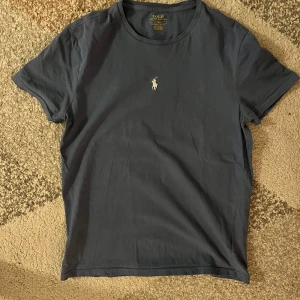 Blå  t-shirt från Ralph Lauren - Säljer en stilren blå t-shirt från Ralph lauren, den är lite använd men fortfarande i bra skick och storlek m. 