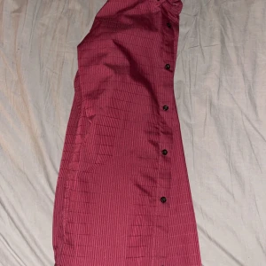 Vinröd skjorta - Snygg vinröd skjorta med diskreta ränder och svarta knappar. Perfekt för en stilren look. Skjortan har långa ärmar och en klassisk krage.