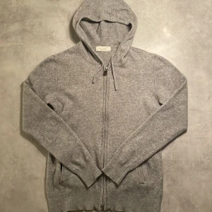 Grå cashmere hoodie - Säljer en stilren grå hoodie med dragkedja och huva. Det är 100% cashmere från sayless. Priset är inte hugget i sten