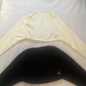 Vit och svart bolerotopp från SHEIN - Två snygga bolerotoppar från SHEIN i vit och svart. De är stickade och har långa ärmar, perfekta att ha för tillexempel ett linne. Den vita koftan är helt oanvänd och den svarta är använd 1 gång, inget plastigt material och är varma att ha på armarna. Tröjorna är i storlek S💗💗💗💗