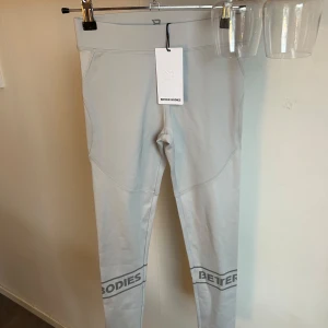 Grå leggings från Better Bodies - Snygga grå leggings från Better Bodies med logotypdetaljer vid anklarna. Perfekta för träning med en tight passform som ger bra stöd. Tillverkade i ett stretchigt material för maximal komfort.