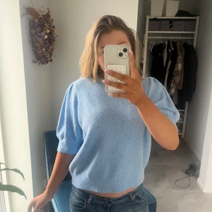 Ljusblå tröja från Vero Moda - Säljer en ljusblå tröja från Vero Moda med korta ärmar och en mjuk, stickad känsla. Perfekt för en avslappnad stil. Tröjan har en enkel design som gör den lätt att matcha med olika outfits.