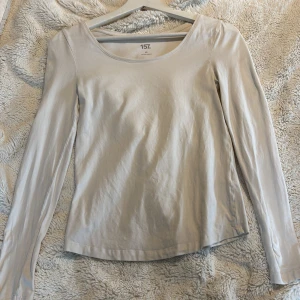 Vit långärmad topp  - Säljer en stilren vit långärmad topp från lager 157. Toppen har en Uringad halsringning och är gjord i ett mjukt material som känns skönt mot huden.