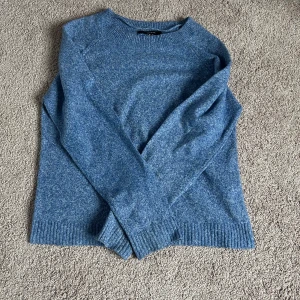 Blå stickad tröja - Mysig blå stickad tröja med rund hals och långa ärmar. Perfekt för kyligare dagar med ribbade muddar vid ärmslut och nederkant.