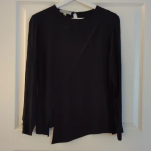 Dagmar svart blus - Fin blus från Dagmar, tidigare kollektion, smal passform med något öppen rygg, knapp i halsringning bak.