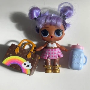 LOL suprise OMG docka med tillbehör  - LOL Surprise OMG docka med tillbehör. Dockan har lila hår och bär en rosa och vit klänning. Tillbehören inkluderar en väska och en nappflaska.