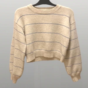 Beige randig stickad tröja - Säljer en supermysig beige stickad tröja med diskreta ränder i blått. Den är croppad och har långa ärmar med ribbade muddar. Perfekt för höst och vår när du vill vara både stilren och bekväm. Passar till både jeans och kjol!