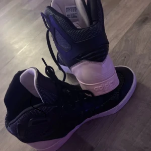 Svarta Adidas sneakers - Säljer ett par svarta Adidas sneakers i storlek 38. De har en cool design med vita detaljer och snörning. Perfekta för vardagsbruk eller träning. Skorna är i bra skick och redo för nya äventyr!