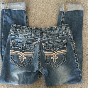 Rock revival jeans⁉️⁉️⁉️🙏🙏 - Säljer ett par snygga blå jeans från Rock Revival med coola broderade detaljer på bakfickorna😻 dom har små defekter och hål men ingenting man lägger märke till, skriv om ni vill ha bild på dom🙏sitter baggy