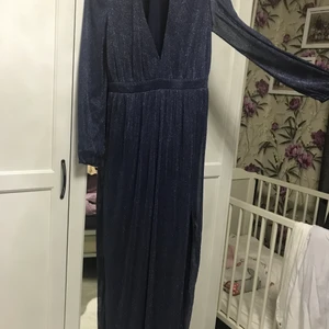 En glitter blå klänning - Klänningen är blå med guld glitter. Klänningen har storleken XL och är använt 1 gång. Klänningen har också ett fint hål från början av benet till foten. Alltså på den vänstra benet. 