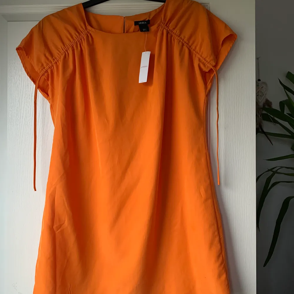 En fin orange klänning! Kan spännas vid axlarna! Helt ny med prislapp kvar! Köpt på Lindex! . Klänningar.