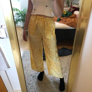 Blommiga byxor från Vila - Supersköna somriga byxor med gula blommor från Vila. Använda 1-2 gånger. Riktigt luftiga vilket gör de perfekta för sommaren. 