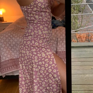 Blommig långklänning  - Rosablommig klänning från shein. Hög slits och justerbara axelband som man knyter. Förslutning i sidan. Strl M, passar även S. 50kr