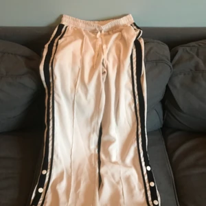 Vita byxor Chiquelle  - Vita byxor med svarta ränder och knappar längst ner på sidorna från Chiquelle. Begagnade men i gott skick, storlek S 🖤🤍