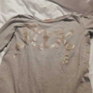 En tröja  - En grå tröja där det står rock på men hål i armen så snygg har ibte använt den sen jag fick den av min kompis. 