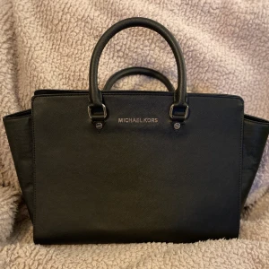 Michael Kors Väska  - Säljväska från Michael Kors med storlek 35X25CM. Berwarna hitam. Den långa remmen var trasig, men ändå bra för användning utan rem.