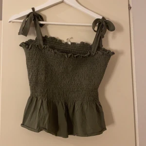 Grönt gulligt linne  - Ett grönt linne som har fina rosetter på armarna som man själv kan knyta hur man vill! Aldrig använt, köpte i somras. Så i nyskick. Passar på mig som är en S/M