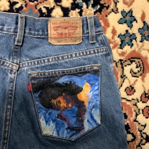 Vintage custom Lorde Melodrama 550 raka Levi’s jeans  - Vintage custom raka Levi’s jeans i modellen 550 med Lorde’s album Melodrama’s skivomslag på höger bakficka 🎨 Så skön passform men inte nog med det; Lorde’s ikoniska album Melodrama är placerad på höger bakficka och gör ett par vardagliga jeans till någonting intressant och som man kan matcha med vad som helt i och med den varierade färgplaletten! Ser extra bra ut med neutrala varma färger för att komplementera de varma färgerna i skrivomslaget och kontrastera från de kalla tonerna i jeans färgen! Markerade som strl M men har följande nått; midjemått: 73 cm, höftmått: 95 cm, innerbenslängd: 79 cm, byxlängd: 102 cm. Som referens är jag va 177 cm.                                                                   Alla priser är inkl. frakt och alla plagg tvättas innan de skickas iväg