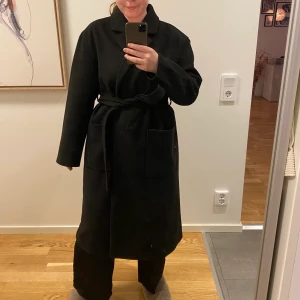 Irma Belted Coat Black strl 38 - Säljer min kappa från gina tricot som jag köpte i höstas som tyvärr inte kommit till användning. Nypris 699kr. Hittar inga noppror, men kan vara tendens till noppror. I fint skick ser inget att anmärka på förutom någon enstaka lös tråd på bandet. 100% polyester PRIS: 500kr inkl frakt💐💐 (Skickas med postnord skicka lätt 2kg då den är tung)