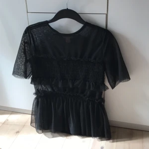  - Topp i tyll från H&M trend  Mycket fint skick! Använd fåtal ggr   Storlek 34 (hyfsat stor i storleken så passar troligtvis 34-36)  Helt i tyll/mesh således lite genomskinliga partier men fodrad över bysten och nedtill vid volangen (flera lager tyg) mesh enbart i ryggen  
