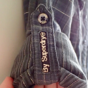  - Grå skateskjorta av SuperDry. Storlek: M men passar även S beroende på hur man vill att den ska sitta (min standardstorlek är S). Skjortan är använd max 3 gånger och säljer den på grund av att jag i princip aldrig har använt den. Köparen står för frakt.