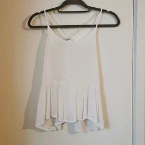 Monki vitt linne i strl XS - Vitt linne med justerbara axelband och volang nedtill från Monki. Strl XS men passar även mig som vanligtvis har strl M. 