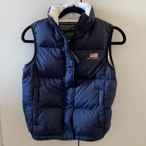 Ralph Lauren väst strl XS - Västen är i storlek Xs men det står S i västen och i väldigt fint skick då jag använt den ett fåtal gånger, innan den blev för liten på mig som är S/M. Västen är mörk marinblå och är en dunväst, så den är varm. På sista bilden ser man en lagning som jag gjort med lapp men det är inget man tänker på. Möts upp i centrala Stockholm och kan självklart frakta men då står köparen för frakten. Vid frågor eller fler bilder är det bara att skriva:) buda gärna och kan också gå ner i pris vid snabb affär;)
