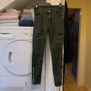 DrDenim cargo byxor i storlek M - Mörkgröna cargo byxor i storlek M med dragkedjor på benen och fickor på sidorna, sparsamt använda