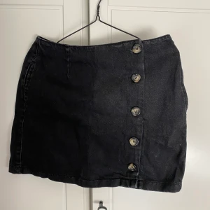 Jeanskjol med knappar - Urtvättad svart jeanskjol med knappar på sidan, ser lite ut som något Rachel i Vänner hade kunnat ha på sig! Tyvärr för stor för mig då den är en strl. 38 medan jag själv har 36. Köpt för två år sedan på Chiquelle, säljer för 130 kr exkl frakt!